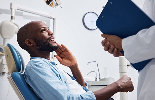 Smiling patient talking to dentist holding clipboard