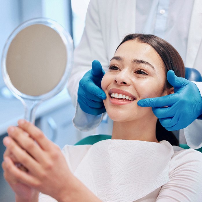 Woman smiling at reflection in handheld mirror