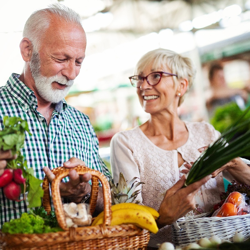 Older man and woman shopping at a farmer’s market for fruits and vegetables