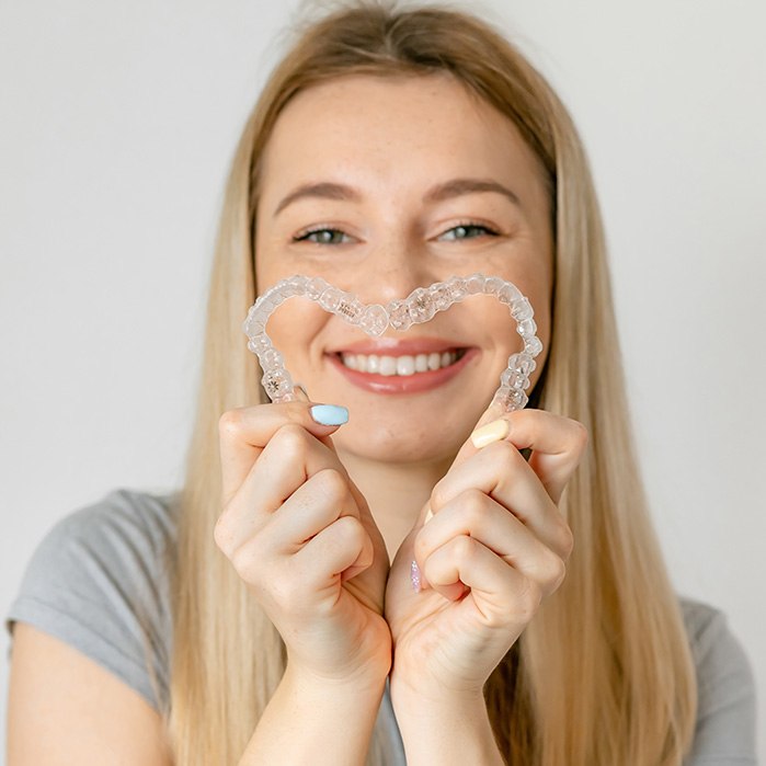 Woman holding two Invisalign aligners in a heart shape