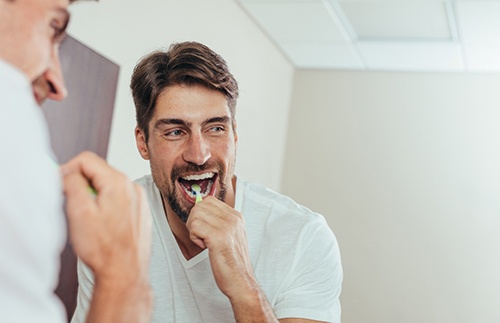 Man smiling while brushing his teeth