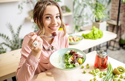 Woman smiling while eating healthy meal in kitchen