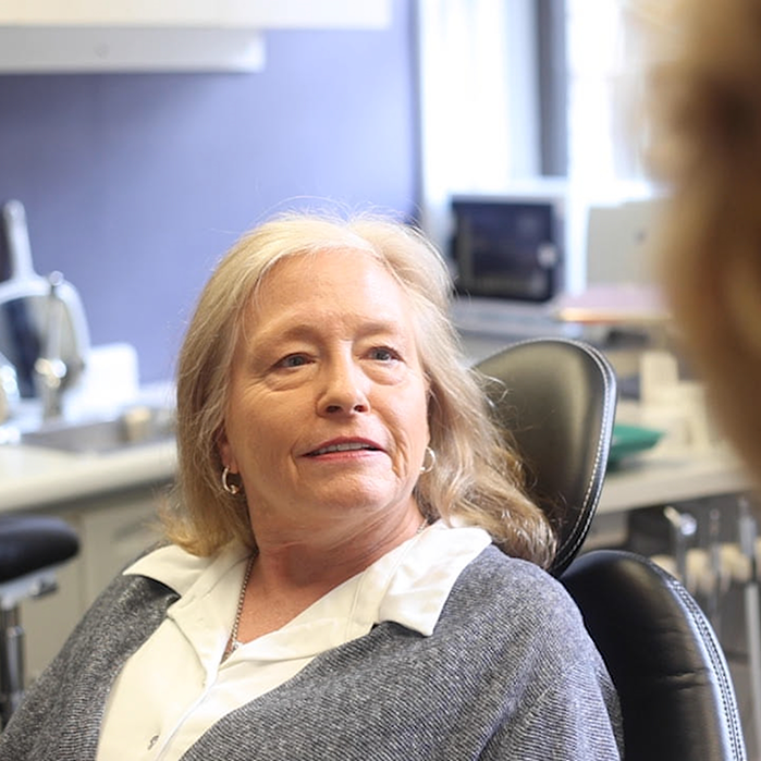 Woman in red shirt laughing in dental chair