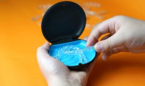 Hand taking Invisalign aligner from its storage case