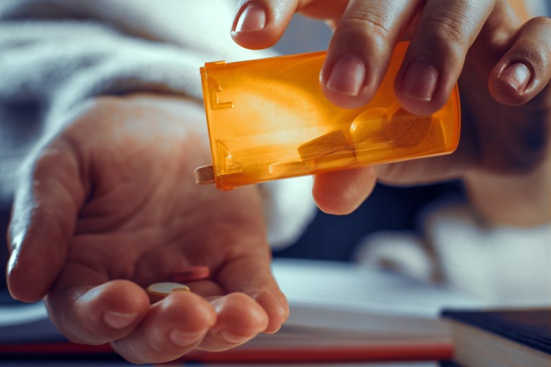 A person gathering medication from a pill bottle
